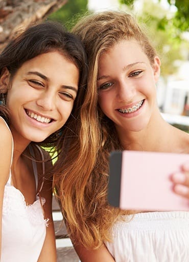 Two girls taking selfie one has braces