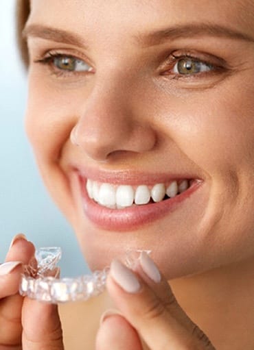 Woman smiling while putting in clear aligners